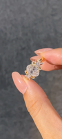 A ring featuring a 2-carat oval lab-grown diamond as the center stone, with a bow-shaped design on the band; graded as D color and VS1 clarity