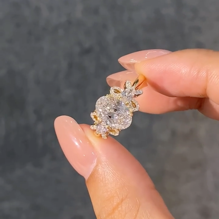 A ring featuring a 2-carat oval lab-grown diamond as the center stone, with a bow-shaped design on the band; graded as D color and VS1 clarity