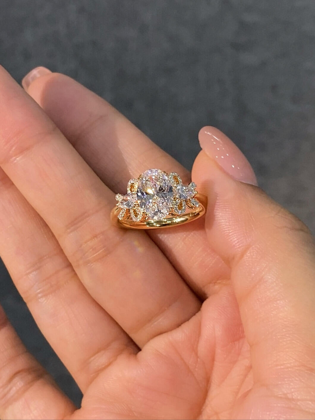 A ring featuring a 2-carat oval lab-grown diamond as the center stone, with a bow-shaped design on the band; graded as D color and VS1 clarity